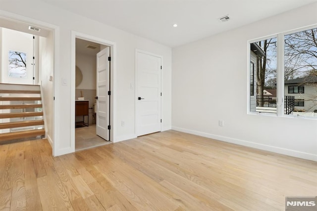 unfurnished bedroom featuring light hardwood / wood-style floors and ensuite bath