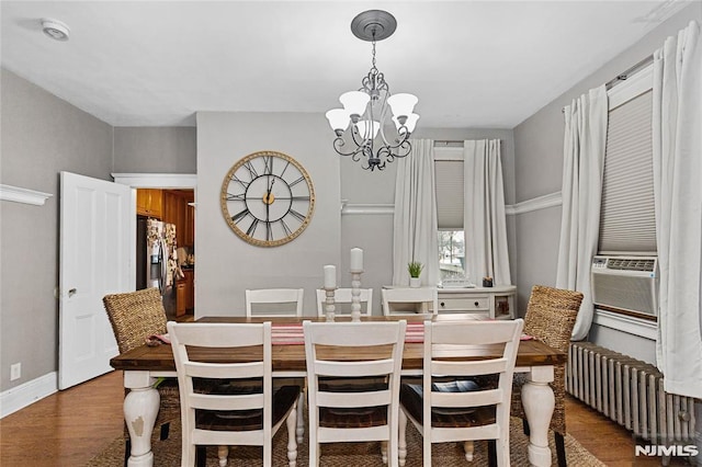 dining space with a notable chandelier, cooling unit, radiator heating unit, and hardwood / wood-style flooring