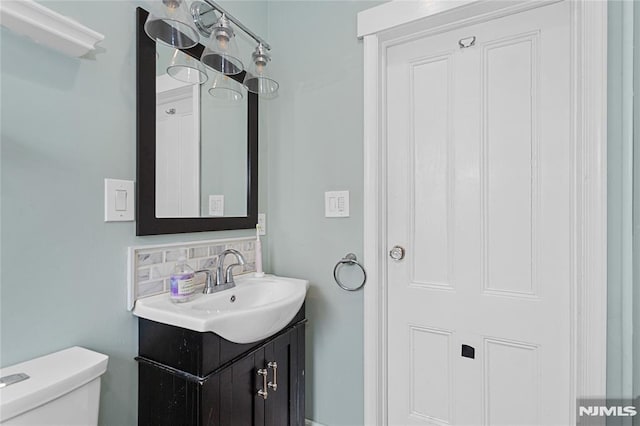 bathroom featuring vanity, decorative backsplash, and toilet