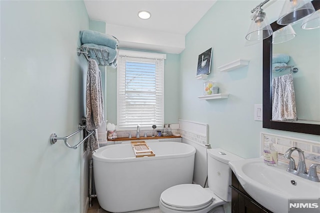 bathroom with toilet, vanity, and a tub