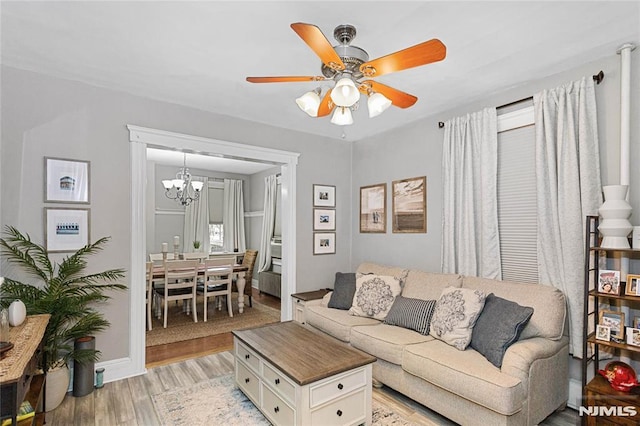 living room with ceiling fan with notable chandelier and light wood-type flooring