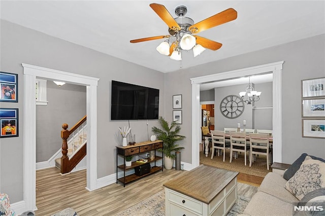 living room featuring ceiling fan with notable chandelier and light wood-type flooring