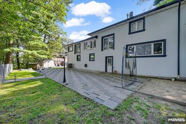 rear view of property featuring a lawn and central AC