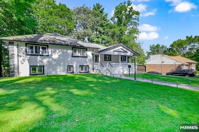 view of front of home with covered porch and a front lawn