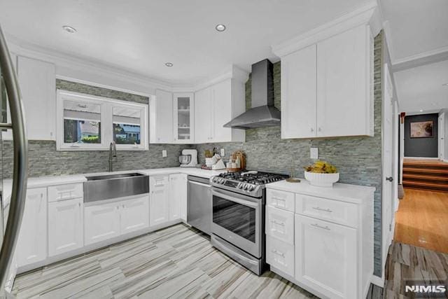 kitchen featuring white cabinets, appliances with stainless steel finishes, and wall chimney exhaust hood