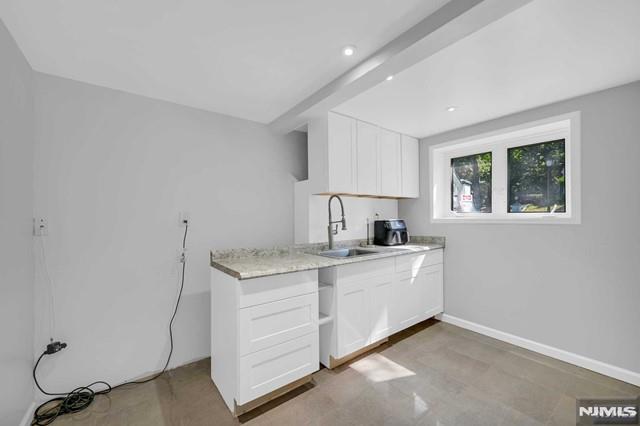 kitchen with white cabinets, sink, and beamed ceiling