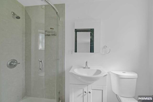 bathroom with a tile shower, vanity, and toilet