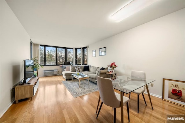 dining space featuring a wall unit AC and light wood-type flooring