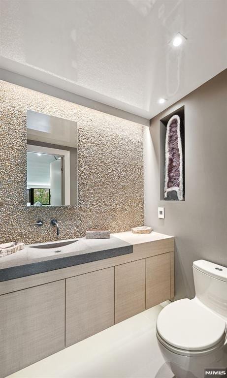 bathroom featuring decorative backsplash, toilet, and vanity