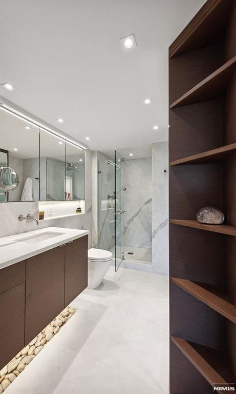 bathroom featuring vanity, an enclosed shower, and toilet