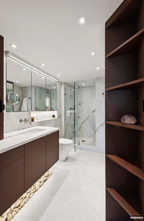 bathroom featuring vanity, toilet, and walk in shower