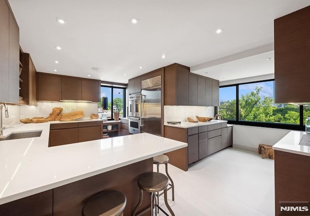 kitchen with kitchen peninsula, a breakfast bar, stainless steel appliances, sink, and plenty of natural light