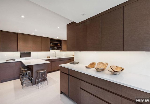 kitchen featuring a breakfast bar, dark brown cabinetry, and sink