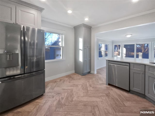 kitchen with light parquet flooring, appliances with stainless steel finishes, gray cabinetry, and ornamental molding