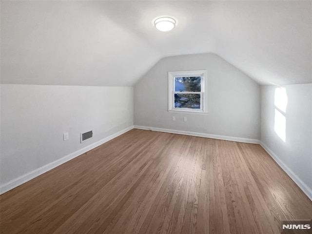 additional living space with lofted ceiling and hardwood / wood-style flooring