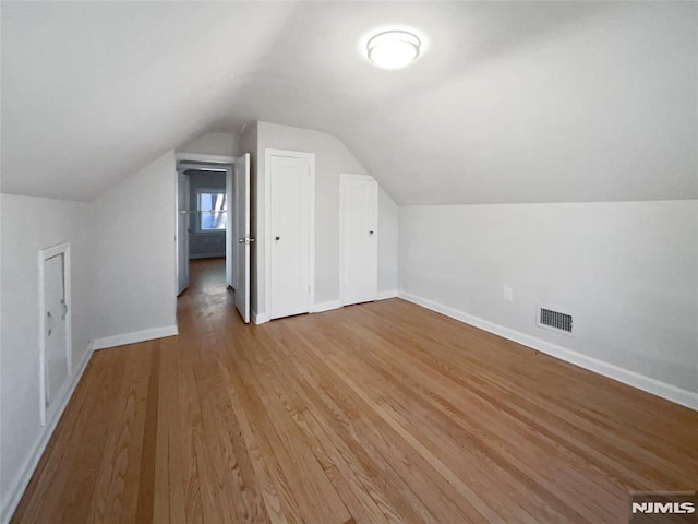 additional living space featuring vaulted ceiling and light wood-type flooring