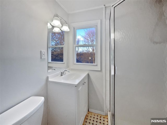 bathroom featuring toilet, vanity, crown molding, and a shower with shower door