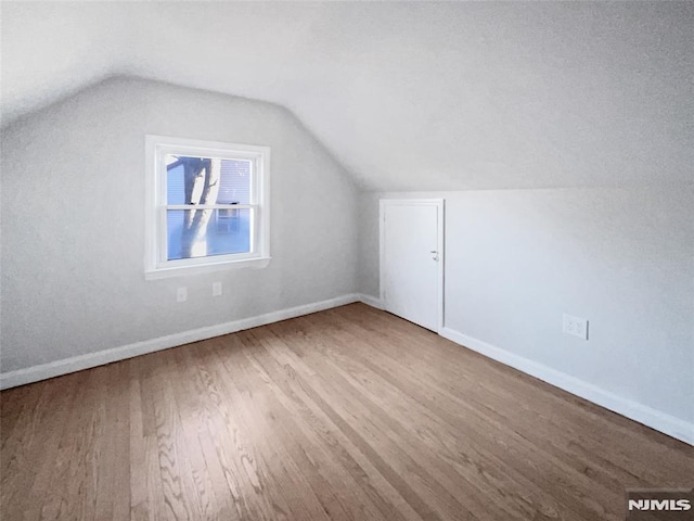 additional living space with wood-type flooring and lofted ceiling