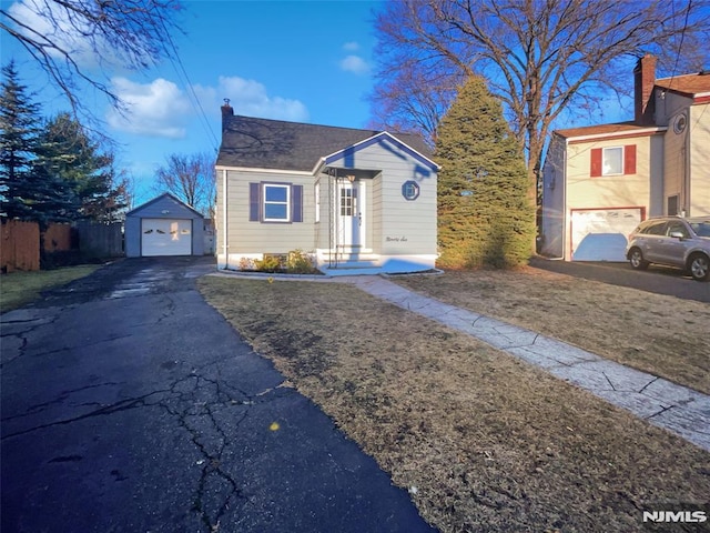 bungalow-style home with a garage, a front yard, and an outbuilding