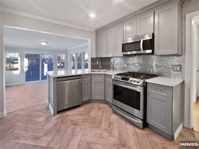 kitchen featuring appliances with stainless steel finishes, gray cabinetry, kitchen peninsula, and sink