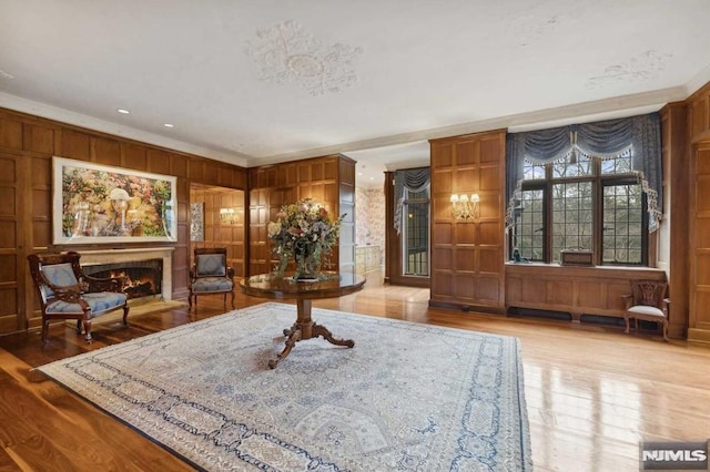 living area with ornamental molding, hardwood / wood-style flooring, and wooden walls