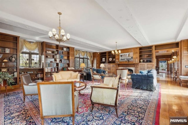 living room with built in features, beamed ceiling, wood-type flooring, and a notable chandelier