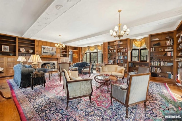 living room with built in shelves, beam ceiling, a notable chandelier, and hardwood / wood-style floors