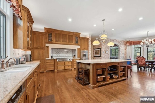 kitchen with sink, hanging light fixtures, a kitchen island, dark hardwood / wood-style flooring, and a breakfast bar area