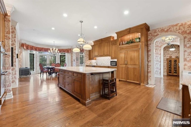 kitchen featuring a center island, tasteful backsplash, a kitchen breakfast bar, pendant lighting, and wood-type flooring