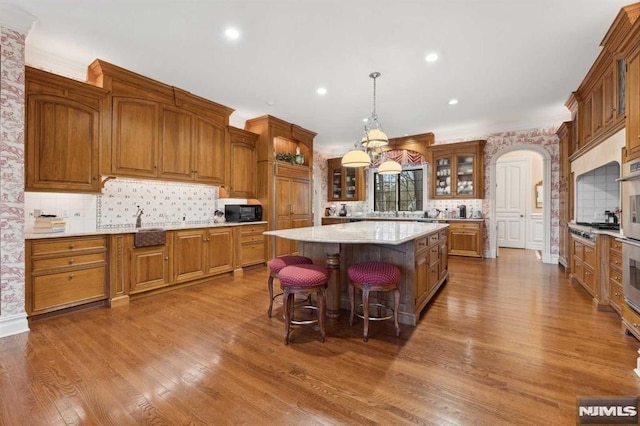 kitchen with pendant lighting, a center island, hardwood / wood-style flooring, and tasteful backsplash