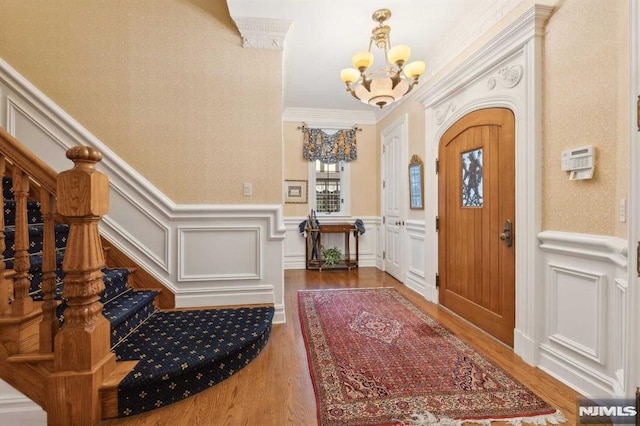 foyer entrance featuring crown molding, hardwood / wood-style floors, and an inviting chandelier