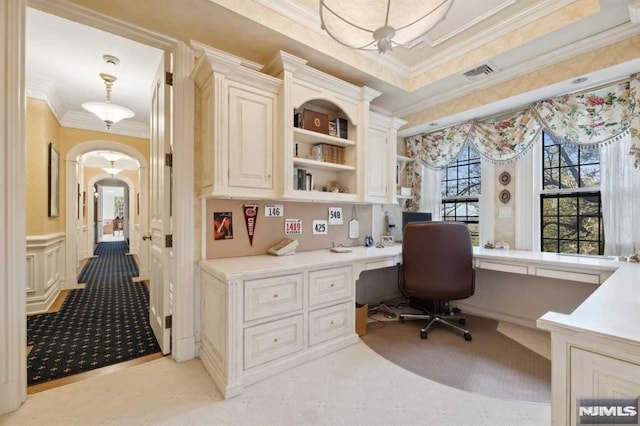 carpeted office space with built in desk and ornamental molding