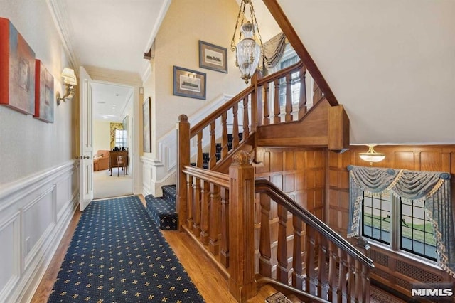 stairs with a chandelier and ornamental molding