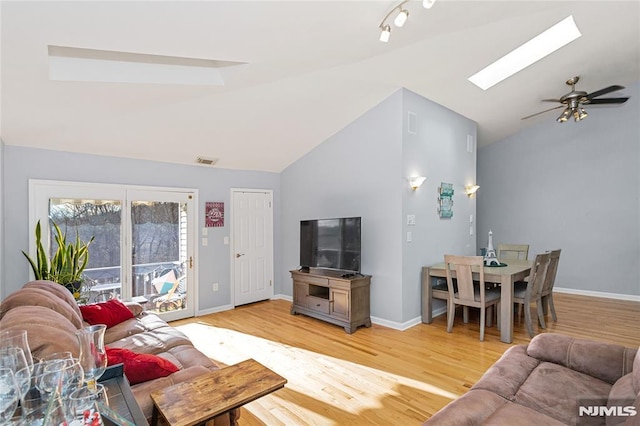 living room with ceiling fan, light hardwood / wood-style floors, and lofted ceiling with skylight