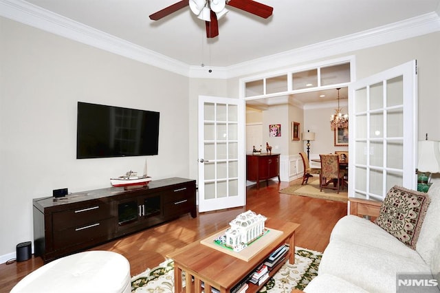 living room featuring french doors, crown molding, hardwood / wood-style floors, and ceiling fan with notable chandelier