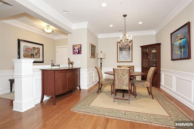 dining area with hardwood / wood-style flooring, an inviting chandelier, and ornamental molding