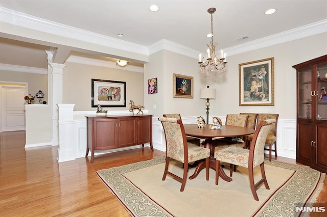 dining room with decorative columns, an inviting chandelier, light hardwood / wood-style floors, and ornamental molding