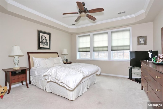 carpeted bedroom with a tray ceiling, ceiling fan, and crown molding