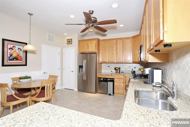 kitchen featuring decorative light fixtures, sink, light stone countertops, and stainless steel appliances