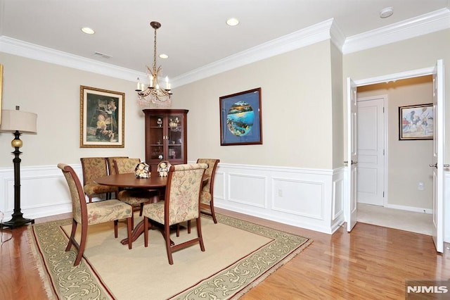 dining area featuring hardwood / wood-style floors, an inviting chandelier, and ornamental molding