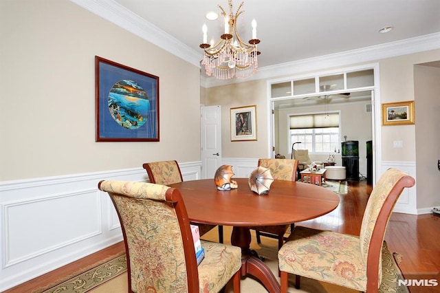 dining area with hardwood / wood-style floors, an inviting chandelier, and ornamental molding