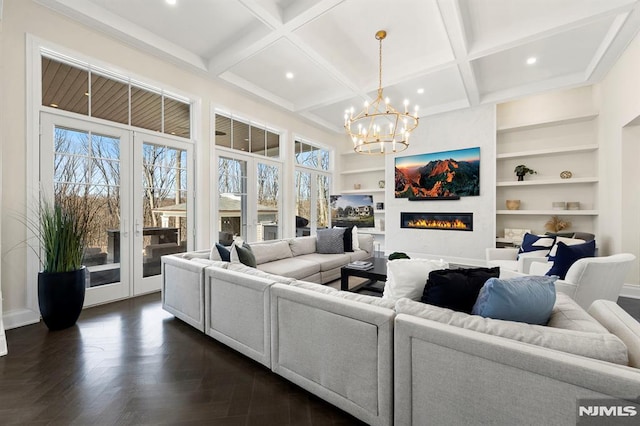 living room with built in shelves, dark parquet floors, and a chandelier