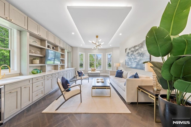 sitting room featuring dark parquet flooring, sink, a tray ceiling, and an inviting chandelier