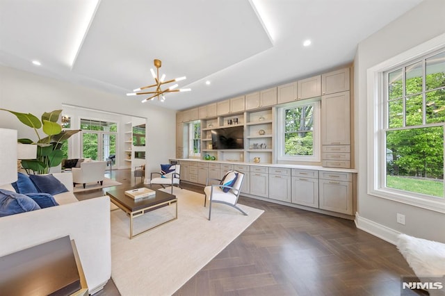 living room featuring a chandelier, dark parquet flooring, and a raised ceiling