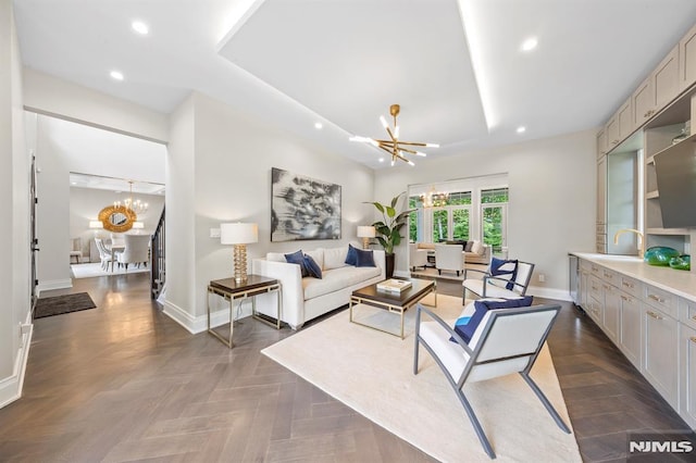 living room featuring dark parquet floors, sink, a tray ceiling, and a chandelier