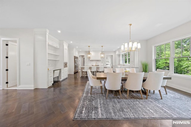 dining space with dark parquet floors and an inviting chandelier