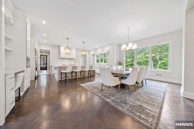 dining room featuring a chandelier and dark parquet floors