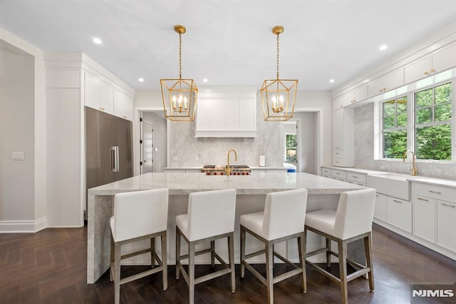 kitchen featuring tasteful backsplash, a spacious island, sink, and hanging light fixtures