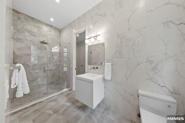 bathroom with vanity, toilet, a shower with door, and tile walls