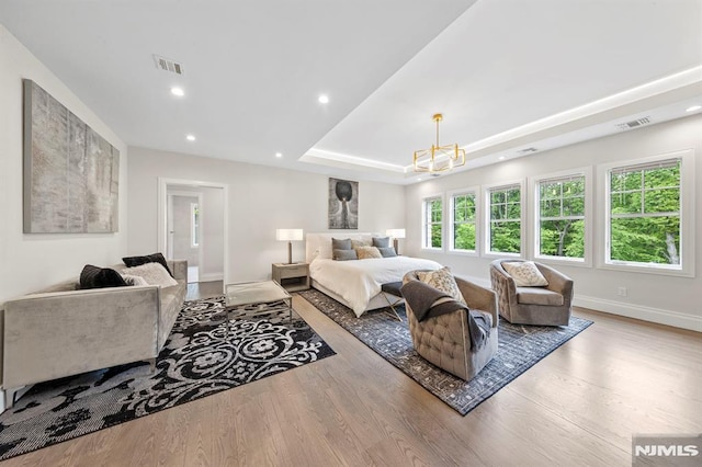 bedroom featuring a chandelier, wood-type flooring, and a raised ceiling